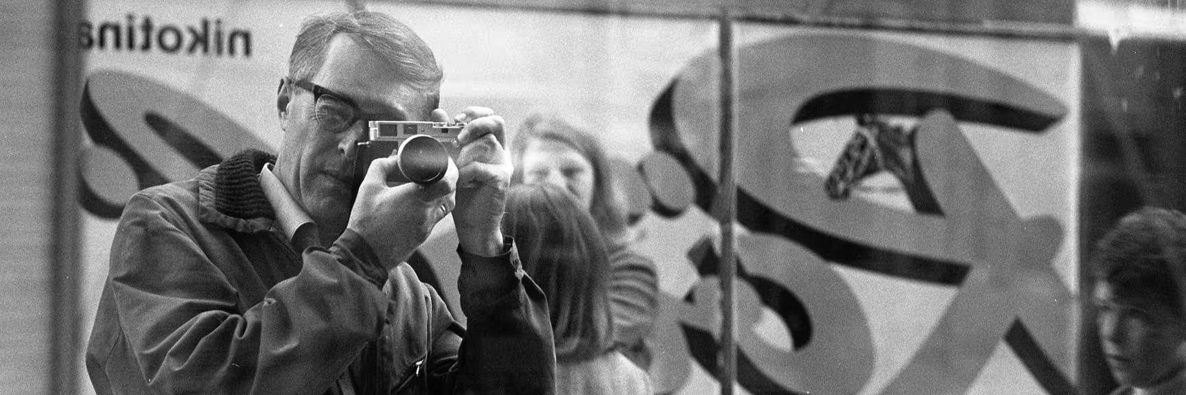 Arnold Renold, sich selber fotografierend, im Hintergrund Plakat Rössli Stumpen (1969) © Bildarchiv Winterthur